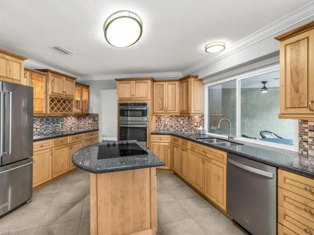 Kitchen with stainless steel appliances, dark stone counters, sink, and a kitchen island