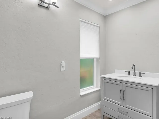 Bathroom with toilet, vanity, and crown molding