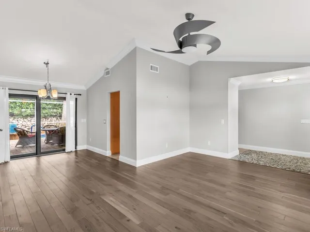 Unfurnished room featuring dark hardwood / wood-style flooring, vaulted ceiling, and ornamental molding