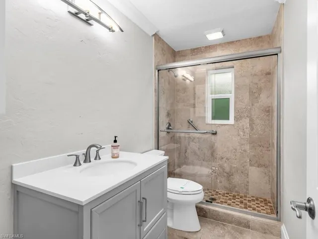 Bathroom with walk in shower, tile patterned flooring, vanity, and toilet