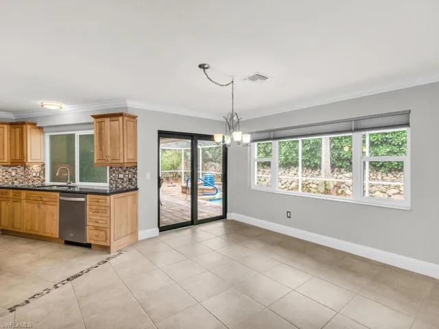 Kitchen with tasteful backsplash, ornamental molding, sink, an inviting chandelier, and stainless steel dishwasher
