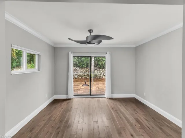 Unfurnished room featuring dark hardwood / wood-style flooring, ceiling fan, and crown molding