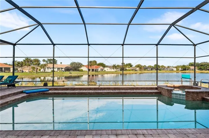 View of pool with a lanai, a water view, and an in ground hot tub