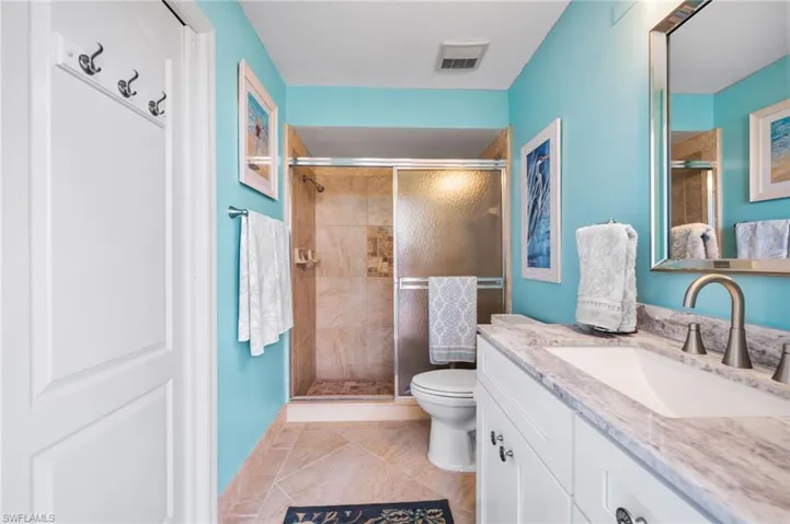 POOL BATH with tile patterned flooring, vanity, toilet, and an enclosed shower