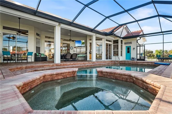 View of swimming pool featuring a lanai, ceiling fan, a patio, and an in ground hot tub