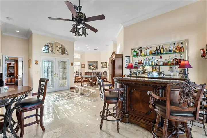 Bar featuring crown molding, french doors, and ceiling fan