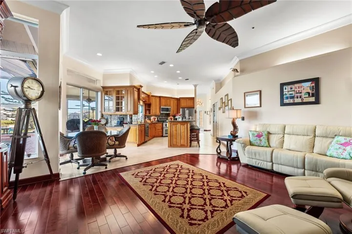 Living room featuring wood-type flooring, ceiling fan, and crown molding