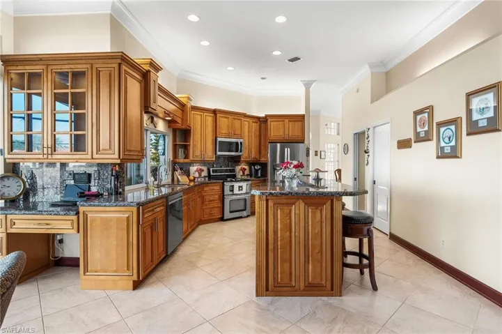 Kitchen with backsplash, a center island, stainless steel appliances, and a kitchen breakfast bar