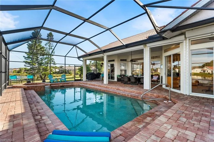 View of swimming pool featuring ceiling fan, a patio area, and glass enclosure