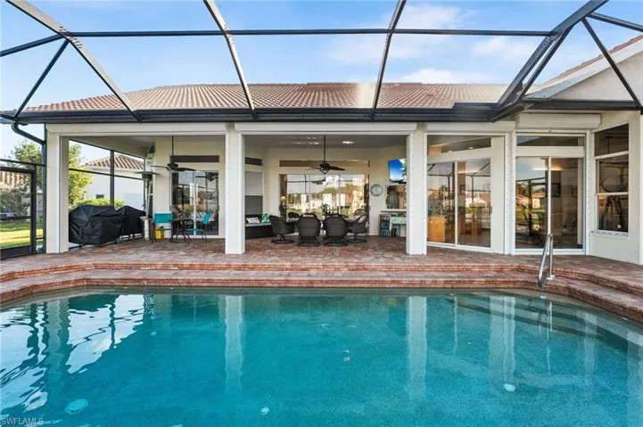 View of pool with ceiling fan, a patio area, and glass enclosure