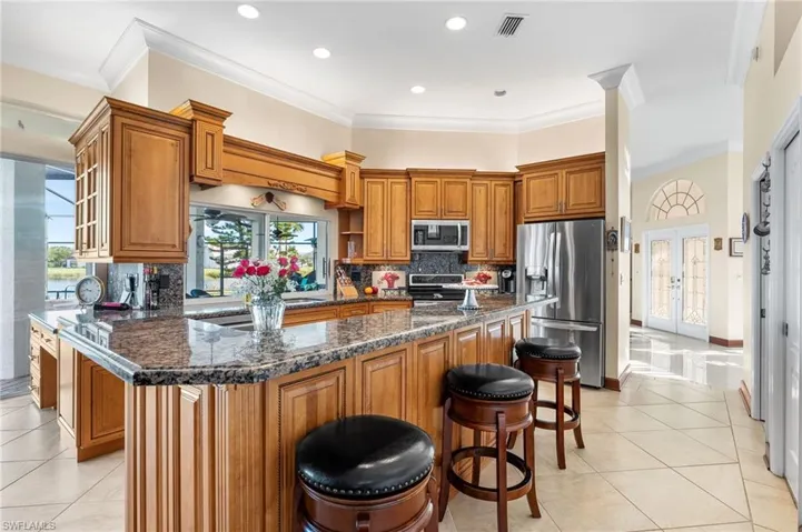 Kitchen with decorative backsplash, appliances with stainless steel finishes, dark stone counters, a center island, and a breakfast bar area