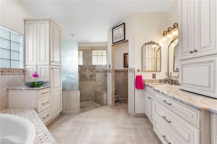Bathroom with vanity, separate shower and tub, and tile walls