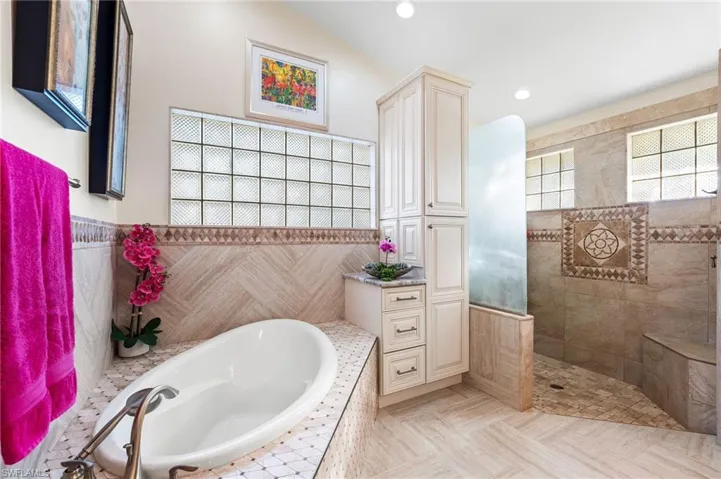 Bathroom featuring vaulted ceiling, tile patterned floors, tile walls, and independent shower and bath
