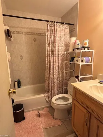 Full bathroom featuring toilet, tile patterned floors, shower / bath combo, and vanity