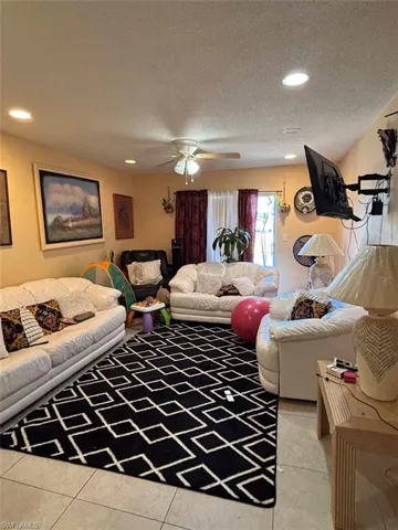 Living room with tile patterned floors, a textured ceiling, and ceiling fan
