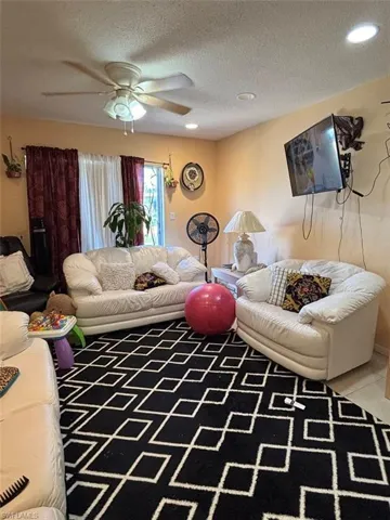 Tiled living room with a textured ceiling and ceiling fan