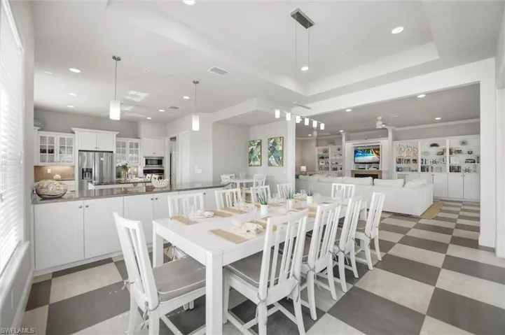 Dining space featuring recessed lighting, a tray ceiling, and light floors