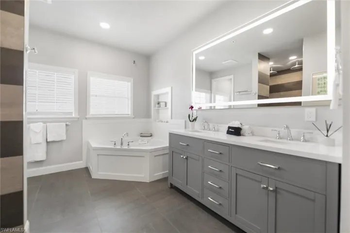 Full bath featuring double vanity, a bath, tile patterned flooring, recessed lighting, and tiled shower
