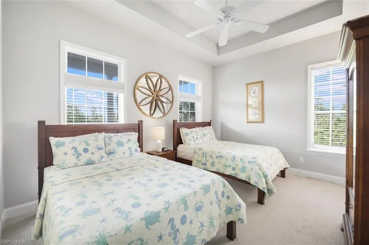 Carpeted bedroom featuring a raised ceiling and ceiling fan