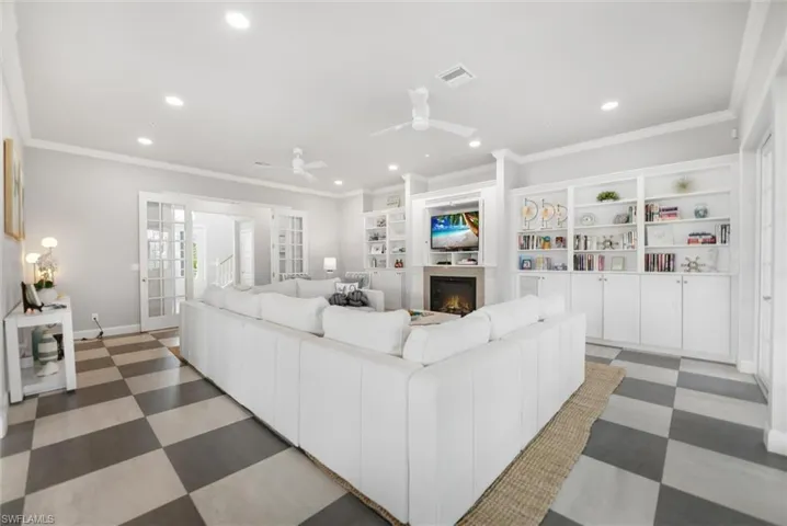 Living area with crown molding, ceiling fan, a lit fireplace, light floors, and recessed lighting
