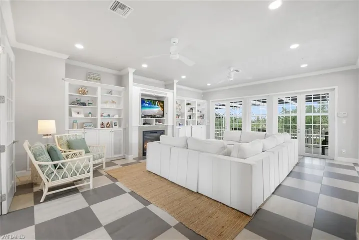 Living room with ornamental molding, recessed lighting, ceiling fan, a glass covered fireplace, and light flooring