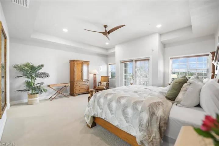 Bedroom with light carpet, recessed lighting, ceiling fan, a tray ceiling, and access to exterior