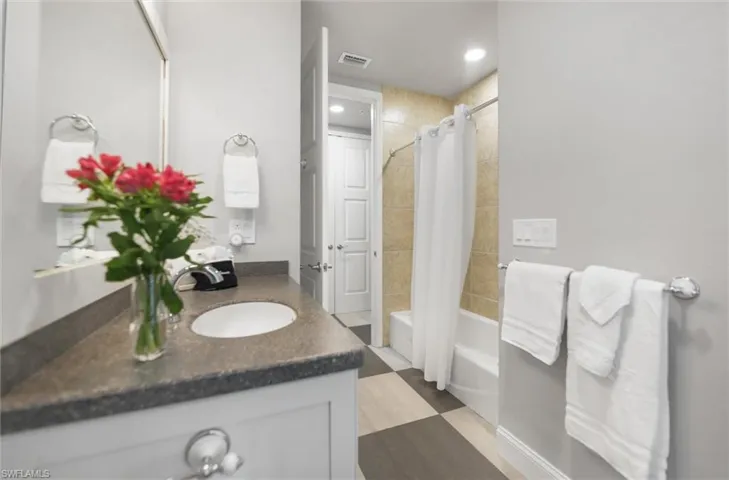 Bathroom featuring vanity and shower / bathtub combination with curtain