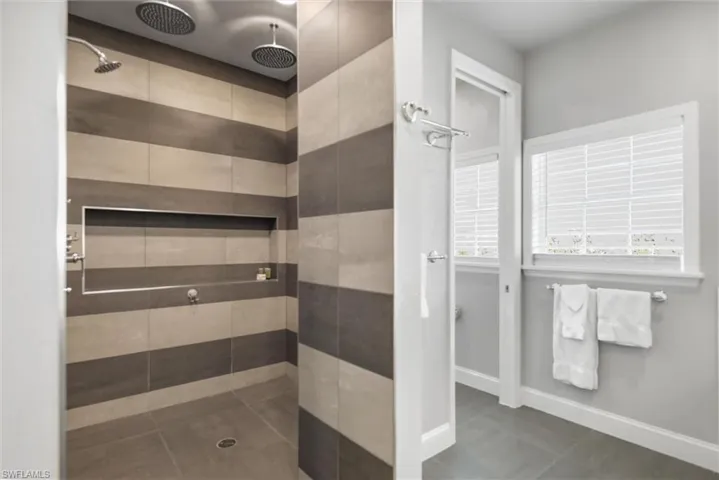 Full bathroom featuring tiled shower and baseboards