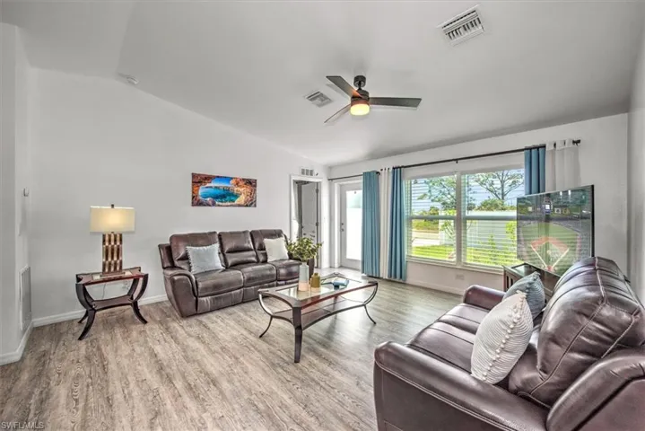 Living area featuring wood finished floors, lofted ceiling, ceiling fan, and visible vents