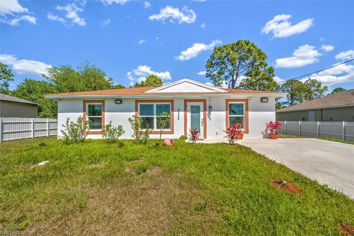 Single story home with stucco siding, fence, and a front lawn