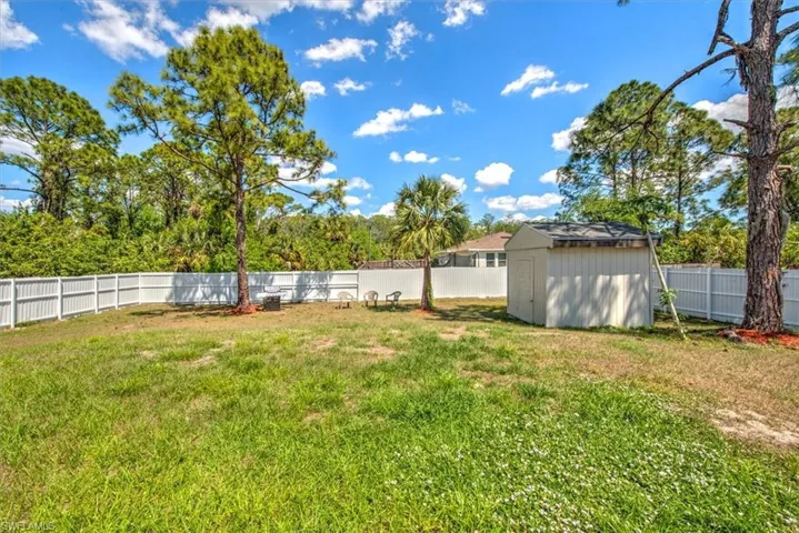 View of yard featuring an outdoor structure, a fenced backyard, and a shed