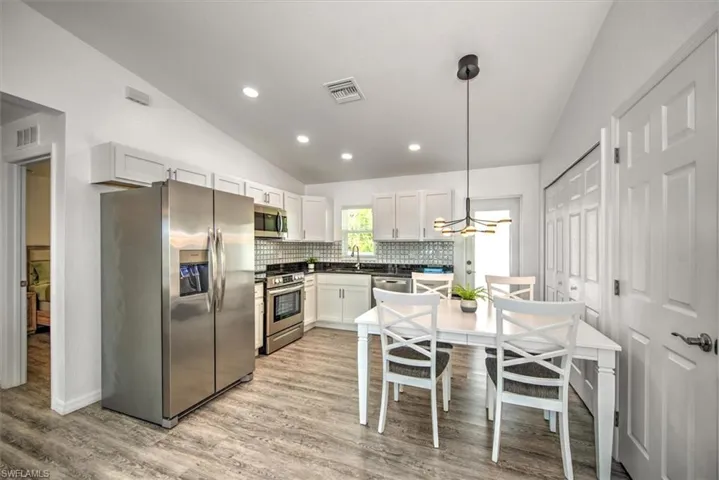 Kitchen with a sink, stainless steel appliances, lofted ceiling, and visible vents