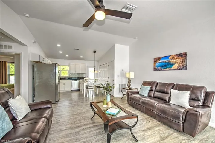 Living area featuring wood finished floors, ceiling fan, vaulted ceiling, and visible vents