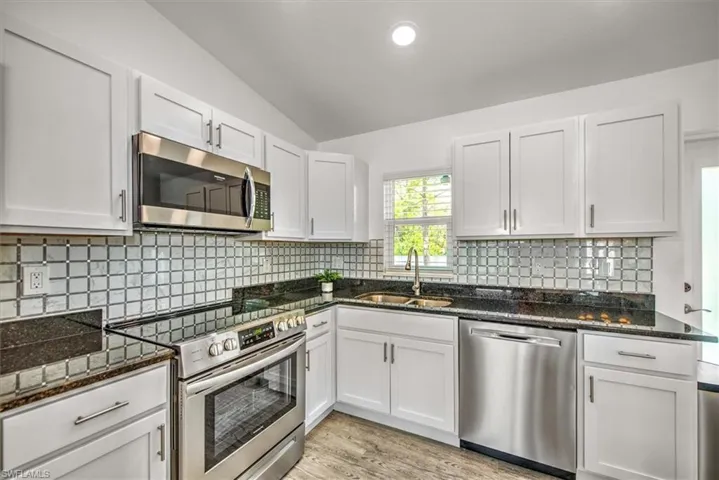 Kitchen featuring a sink, white cabinetry, dark stone countertops, and appliances with stainless steel finishes