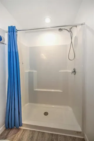 Full bathroom with a shower stall and wood finished floors