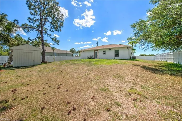 Back of house featuring a fenced backyard, an outbuilding, a storage shed, and a yard