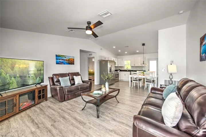 Living area featuring light wood finished floors, visible vents, ceiling fan, and lofted ceiling
