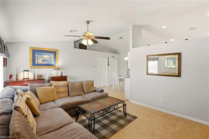 Living room featuring ceiling fan, light tile patterned floors, and high vaulted ceiling