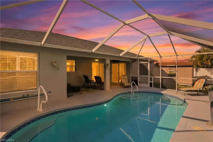Pool at dusk with an outdoor pool, a sunroom, glass enclosure, and a patio