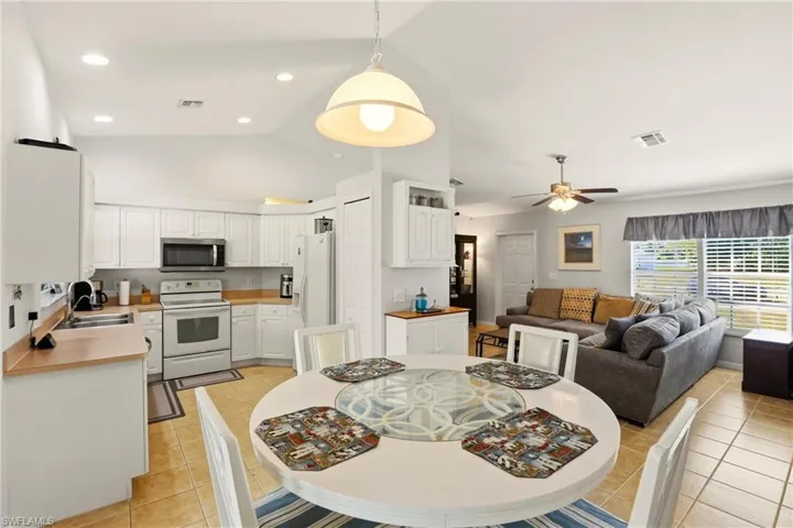 Dining area featuring light tile patterned flooring, ceiling fan, high vaulted ceiling, and recessed lighting