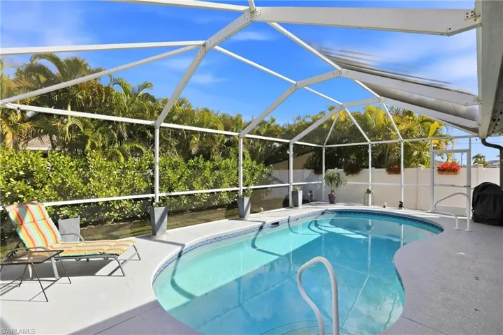 View of swimming pool with glass enclosure, a sunroom, and grilling area