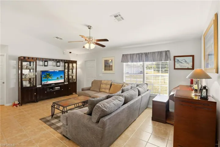 Living room featuring light tile patterned floors, vaulted ceiling, and ceiling fan