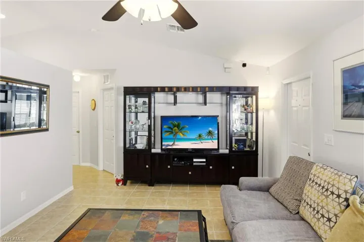 Tiled living room featuring lofted ceiling and a ceiling fan