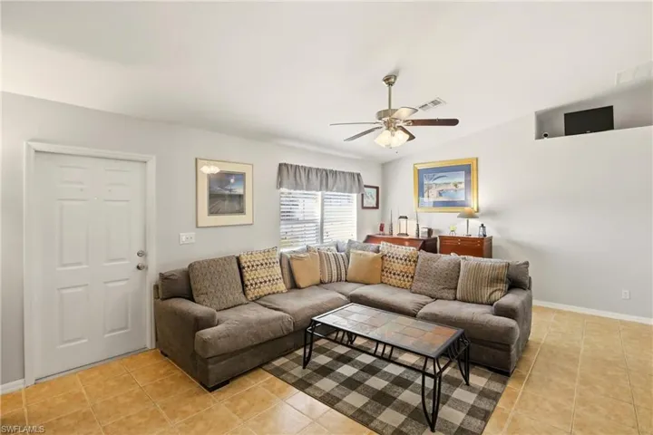 Living room with light tile patterned flooring, lofted ceiling, and a ceiling fan
