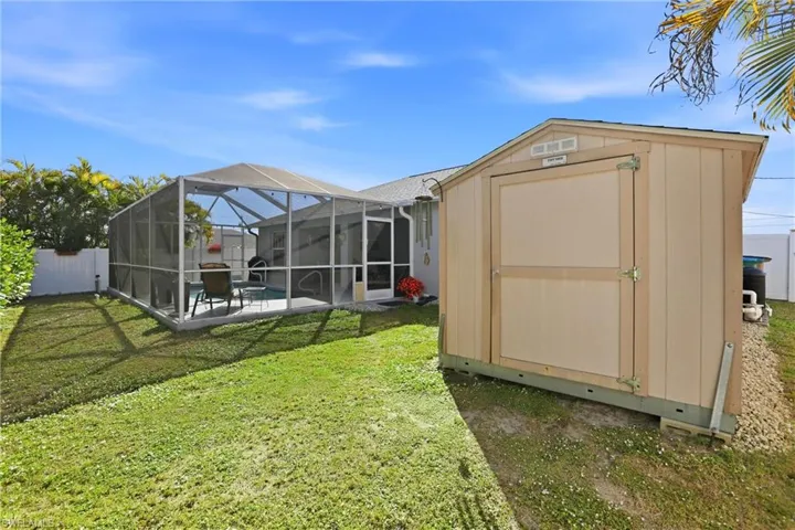 View of shed with a fenced backyard, a sunroom, and a swimming pool