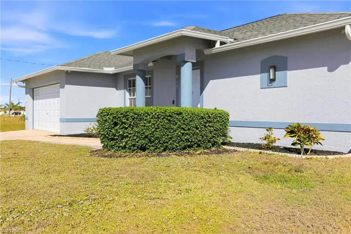 View of side of property with stucco siding, a yard, roof with shingles, and driveway