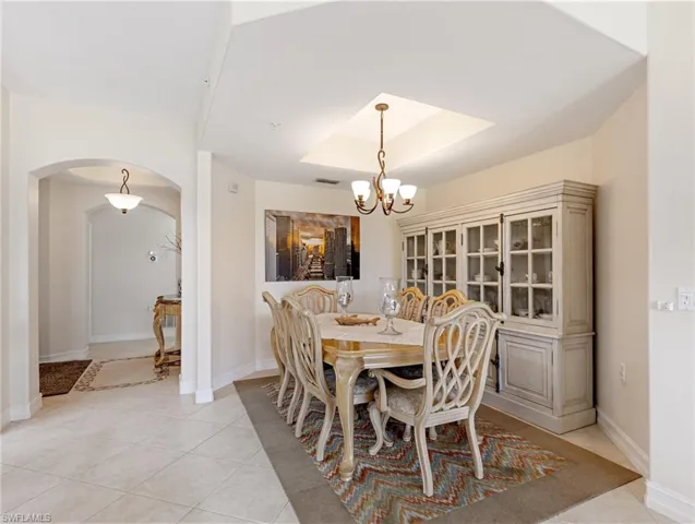 Dining area featuring a raised ceiling, and an inviting chandelier