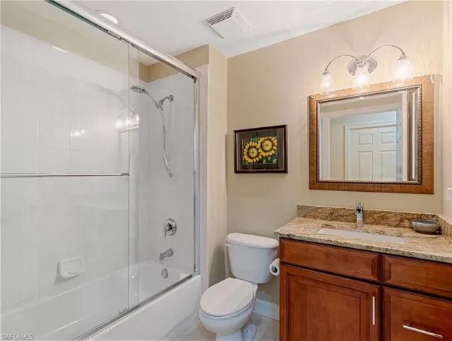 Full bathroom with toilet, shower / bath combination with glass door, granite topped vanity