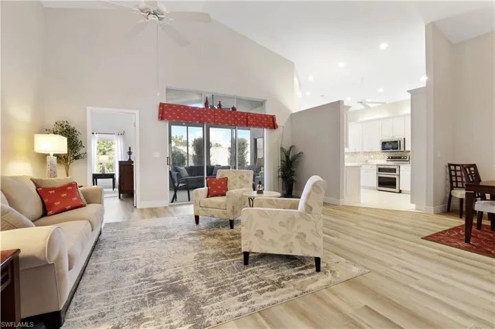 Living room with ceiling fan, high vaulted ceiling, light wood-style floors, and recessed lighting