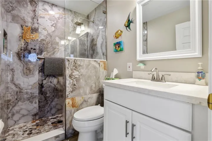 Bathroom featuring vanity and a marble finish shower